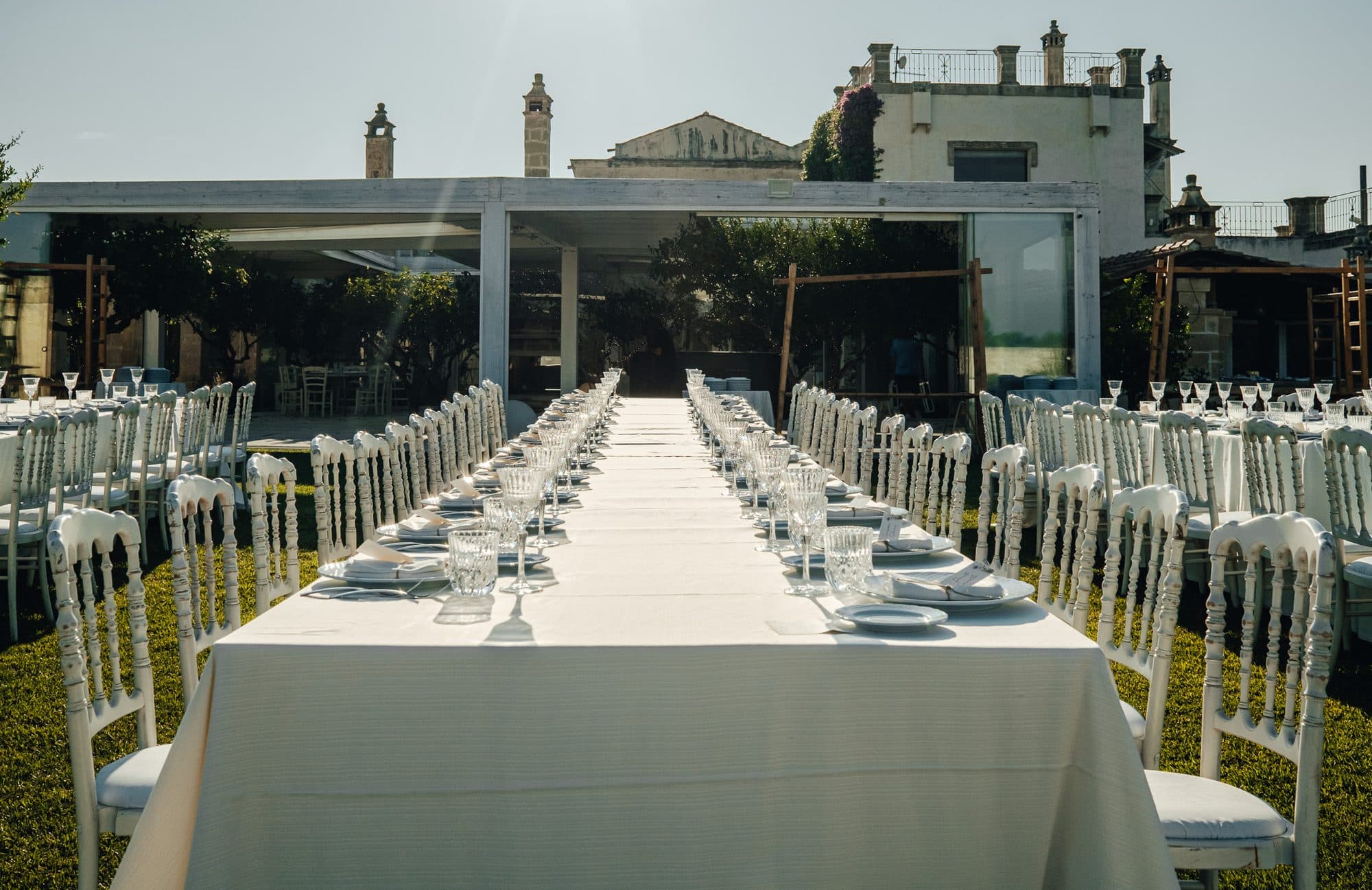 The long table on the lawn, laid in full daylight in front of the masseria